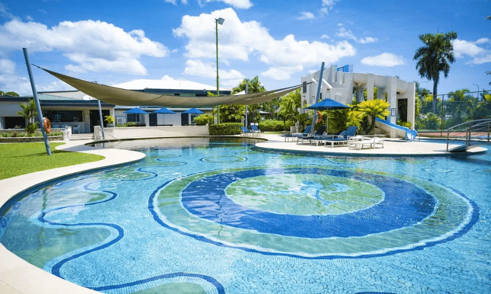 Large lagoon-style swimming pool with mosaic tile design, waterslide, and shaded sun loungers at Fiji Gateway Hotel
